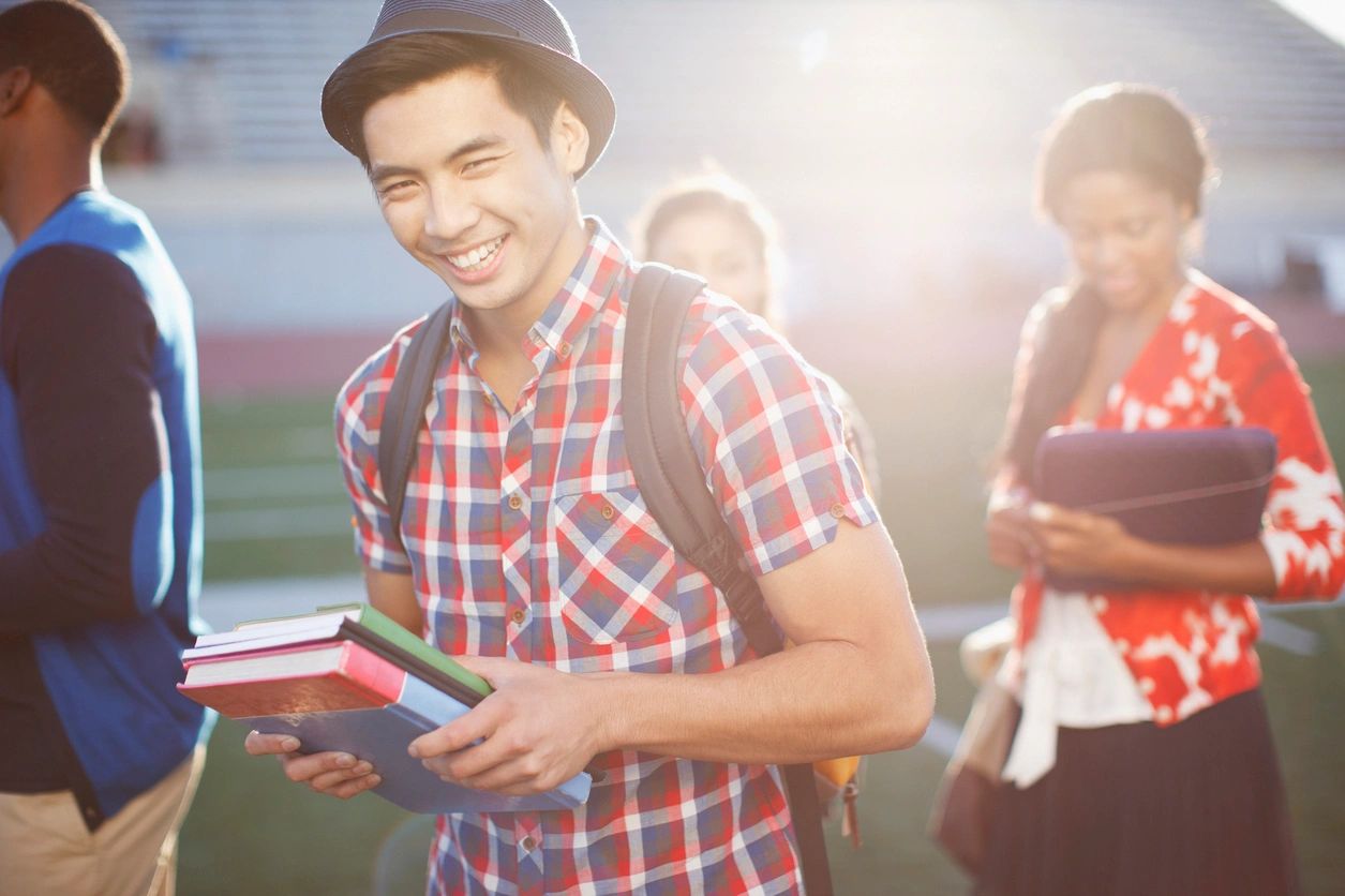 A man holding books and smiling for the camera.