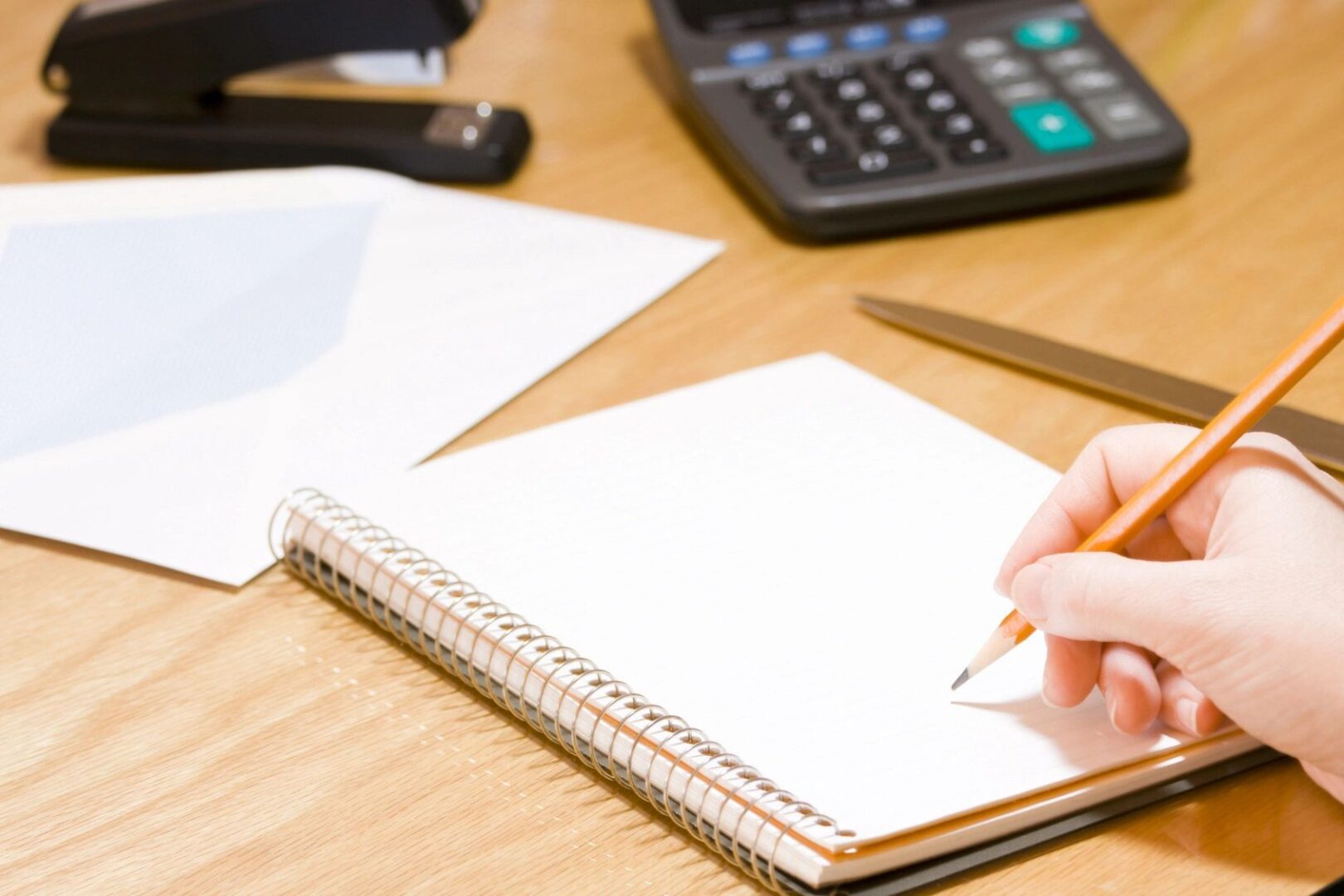 A person writing in a notebook on top of a table.