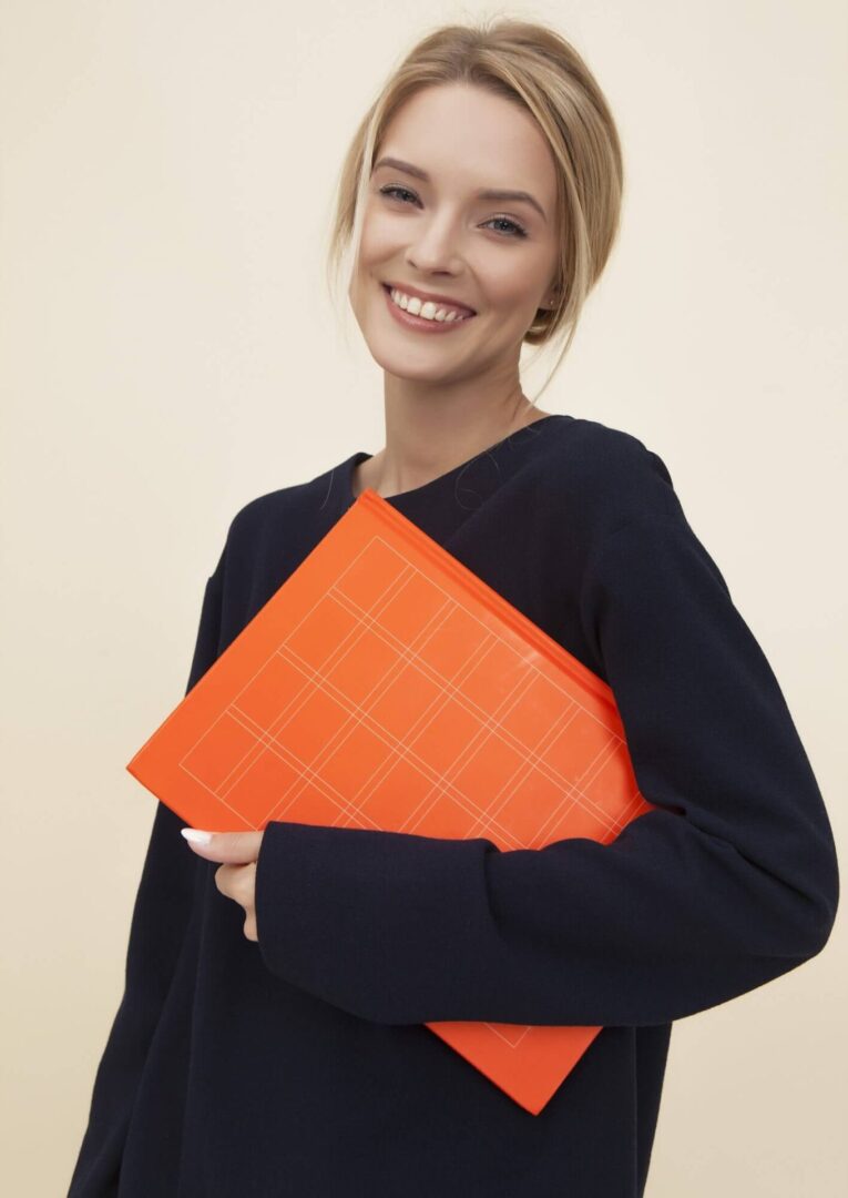 A woman holding an orange folder in her hands.