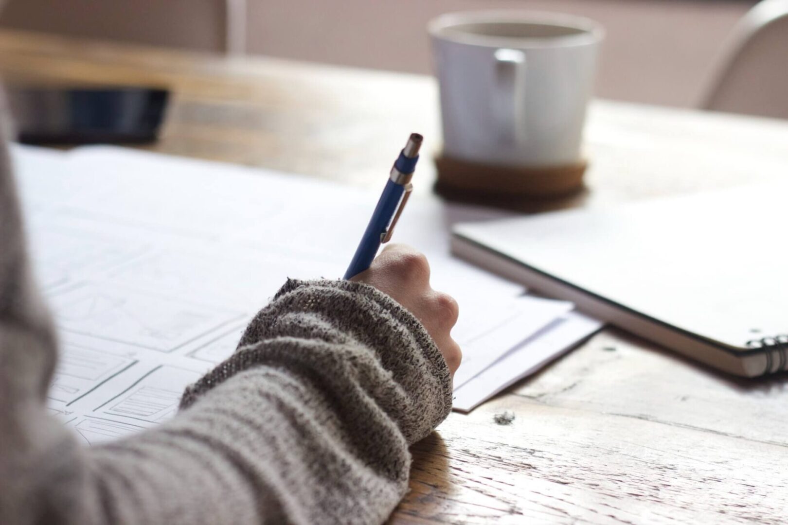 A person writing on paper with a pencil